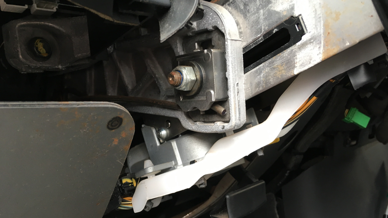The offending lock, visible underneath the steering column and right above the white plastic wire guide. The dreaded shear-head bolt is the shiny dome on the side of the lock, two thirds of the way down this picture